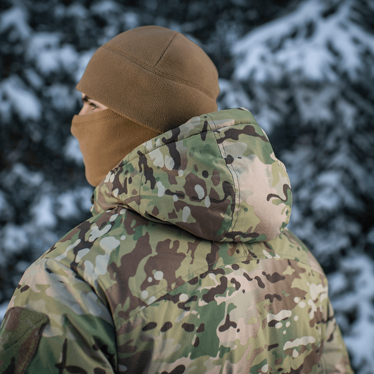 Henkilö M-Tac Alpha Gen.IV Pro Primaloft -takissa Multicam-kuosilla ulkona lumisessa maisemassa.