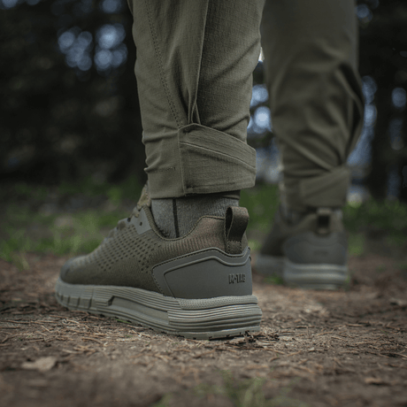 M-Tac Aggressor Summer Flex -housut metsäympäristössä, näyttää lahkeen ja kengän yksityiskohtia