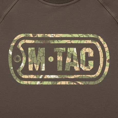 M-Tac Raglan Logo camokuvio ja 'Born by Revolution – Hardened by War' -slogan hihassa, mukavuutta ja tyyliä taktiseen käyttöön