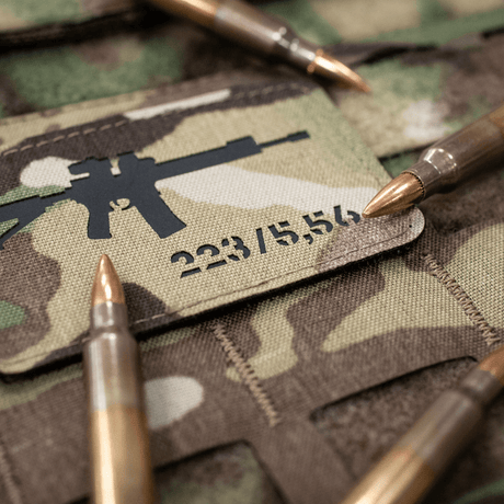 M-Tac AR-15 223/5,56 Laser Cut Patch, sijoitettu maastokuvioon ammusten kanssa, Velcro-takapuoli, Cordura 500D, taktinen ja kestävä ulkokäyttöön.