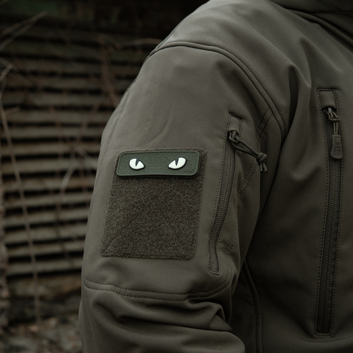 M-Tac Cat Eyes 3D PVC-patch takinhihassa taktillisessa ympäristössä, näyttää heijastavan ja fluoresoivan designin, kiinnitetty Velcrolla.