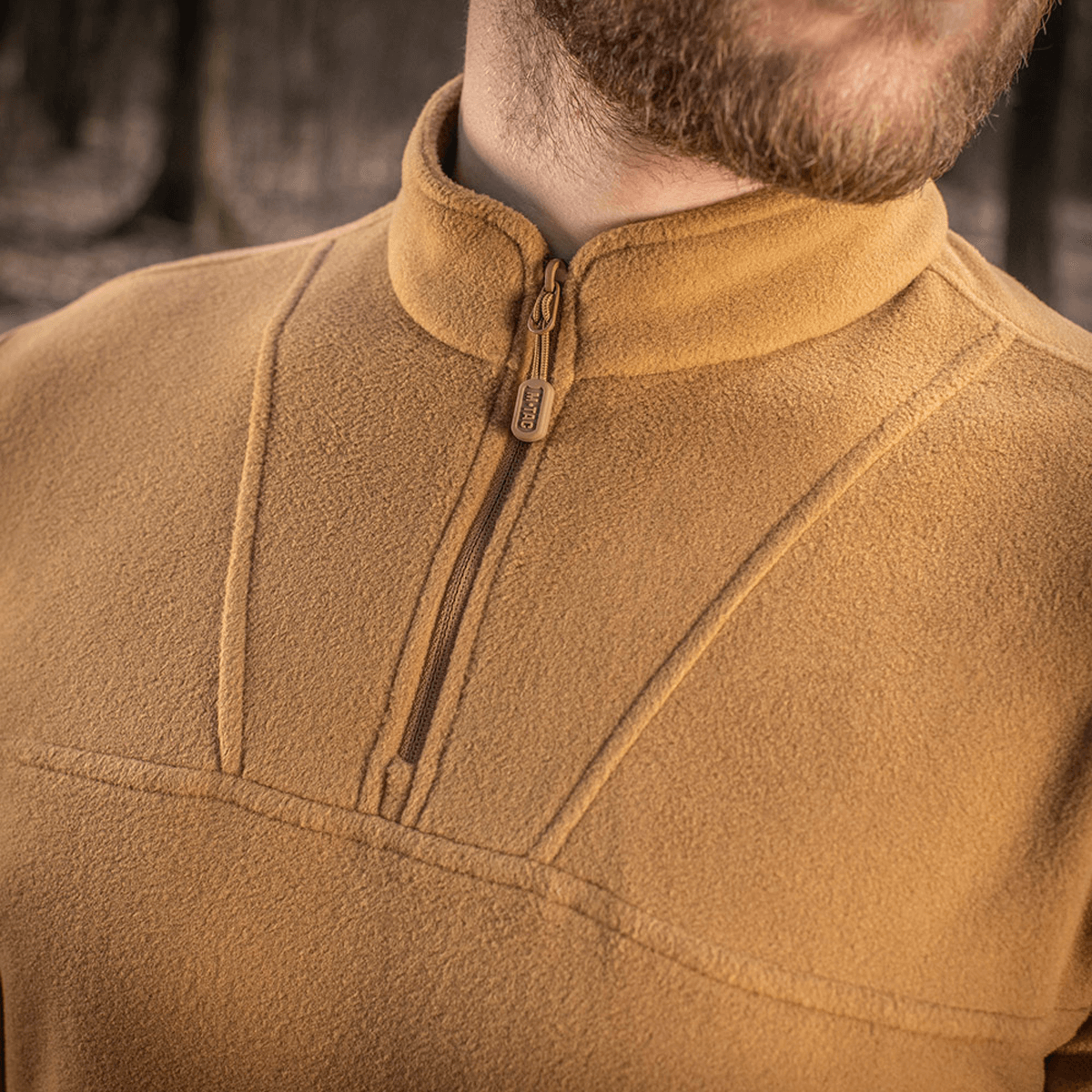 Mies pukeutuneena M-Tac Delta Polartec fleece-takkiin luonnossa, näyttää pehmeän ja lämpimän fleecen puolivetoketjulla kylmiin päiviin.