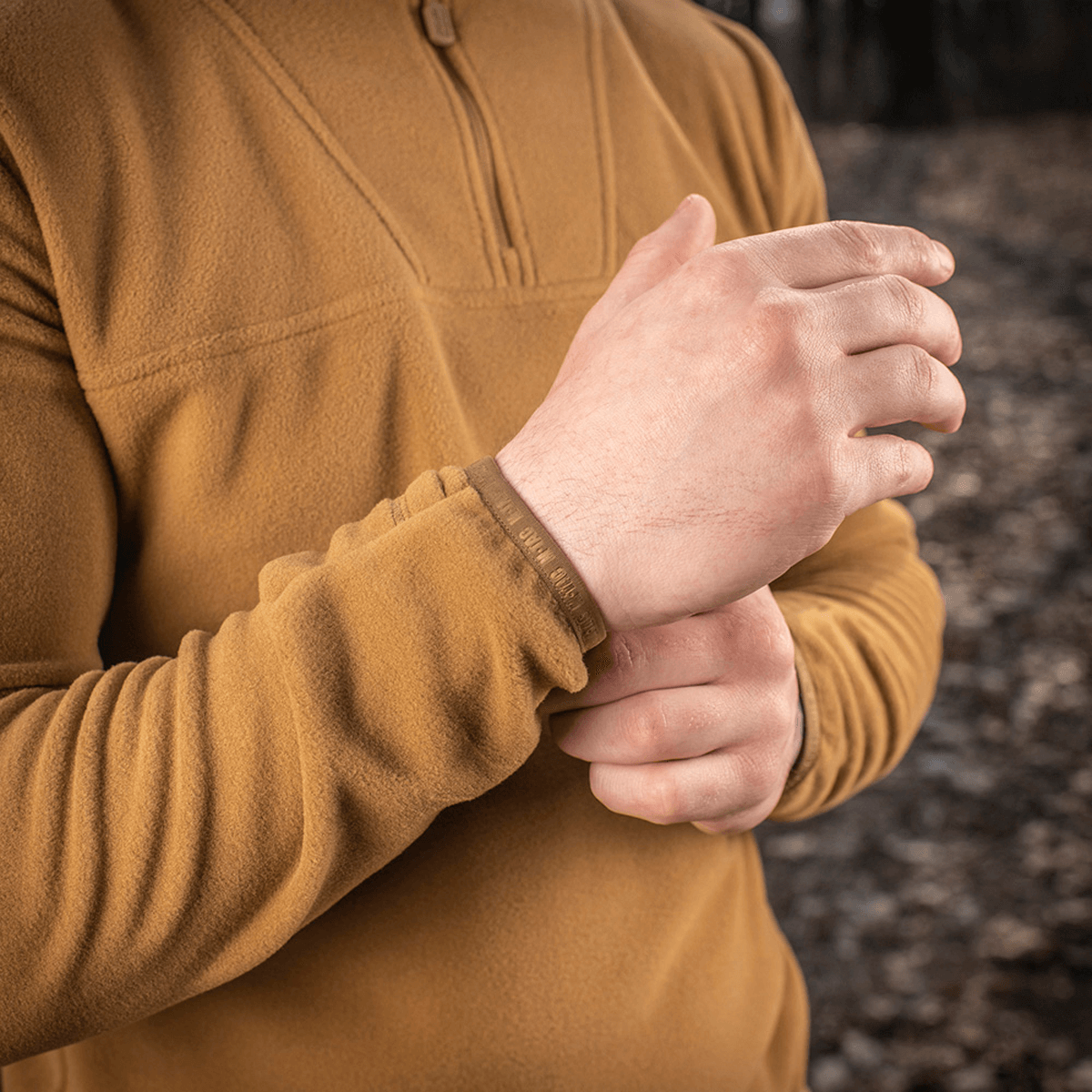 Lähikuva henkilöstä pukeutuneena M-Tac Delta Polartec fleece-takkiin metsässä, korostaa takin pehmeää ja hengittävää materiaalia.