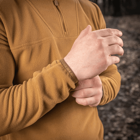 Lähikuva henkilöstä pukeutuneena M-Tac Delta Polartec fleece-takkiin metsässä, korostaa takin pehmeää ja hengittävää materiaalia.