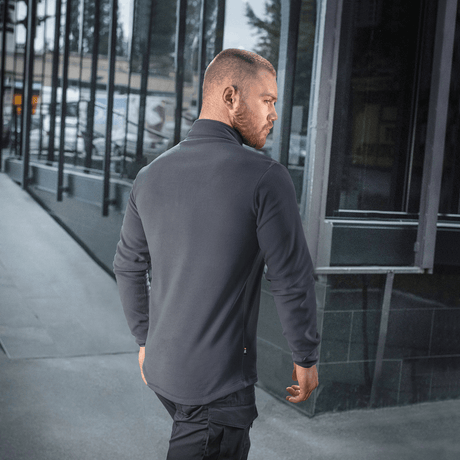 M-Tac Delta Polartec -fleece-takki harmaana, nähtynä takaa miehellä kaupunkimaisemassa.