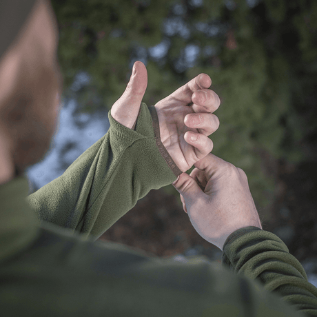Mies pukeutuneena M-Tac Delta Polartec fleece-takkiin säätää hihansuut luonnossa.