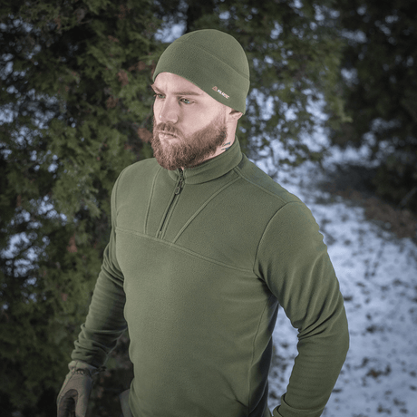 Mies pukeutuneena M-Tac Delta Polartec fleece-takki, metsä ja lumi taustalla, tyylikäs ja käytännöllinen kylmiin päiviin.