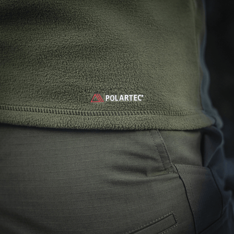 Lähikuva M-Tac Delta Polartec fleece-takista oliivinvihreänä, näkyy Polartec-logo ja kestävä, hengittävä Polartec® Micro Series -fleece.
