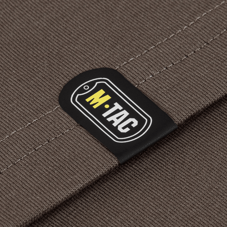 Lähikuva M-Tac T-Shirt Logo Long Sleeve -yksityiskohdasta, M-Tac-logo maastokuvioidulla kankaalla.