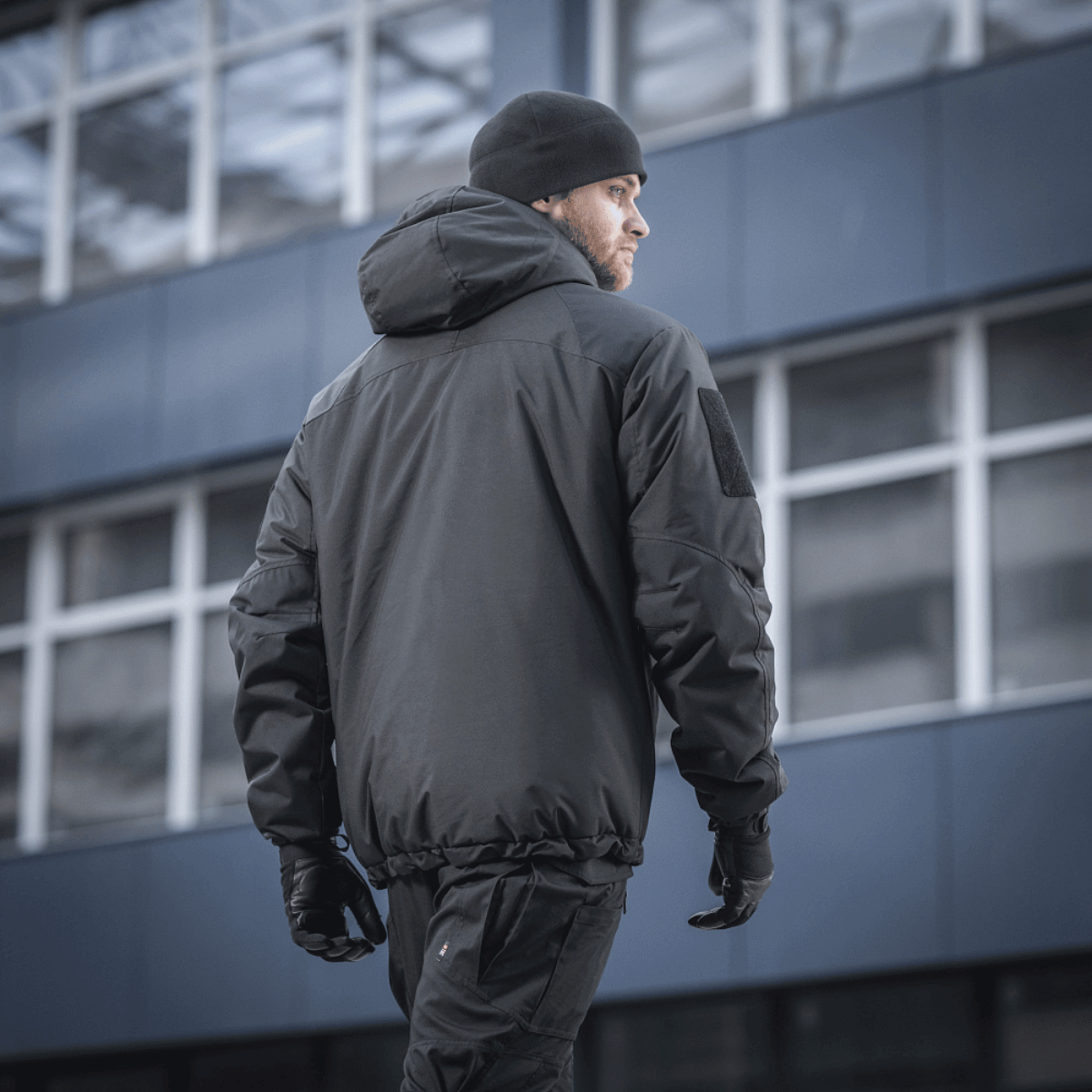 M-Tac Alpha Gen.III Pro -talvitakki, musta, takaa kuvattuna miehellä kaupungissa, suunniteltu äärimmäiseen kylmään ja sateeseen, parannettu G-Loft-täytteellä.