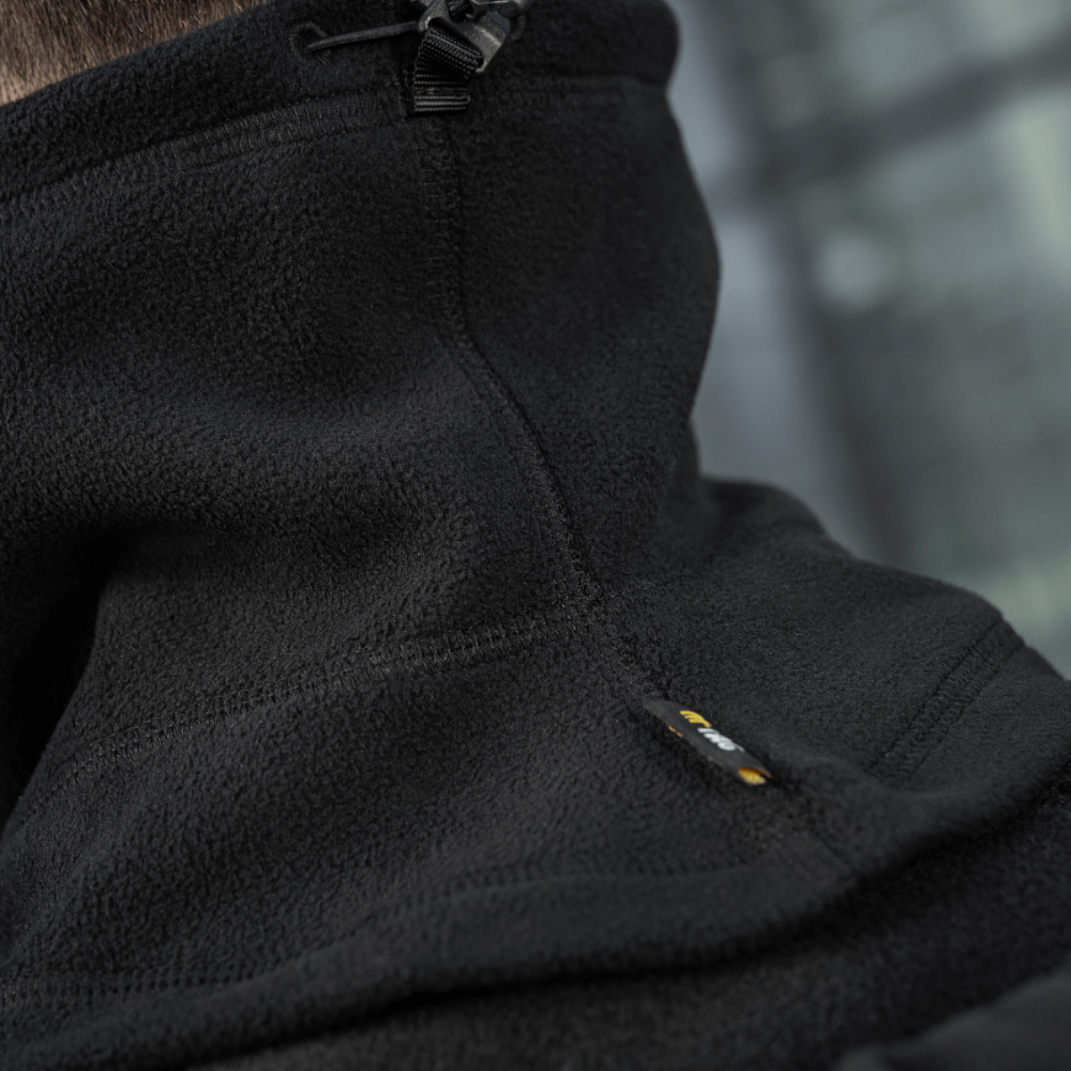 Lähikuva M-Tac Anatomisk Snood Justerbar Elite Fleece (320 g/m²) mustasta fleecestä, näyttää säätönarun ja kestävän materiaalin.