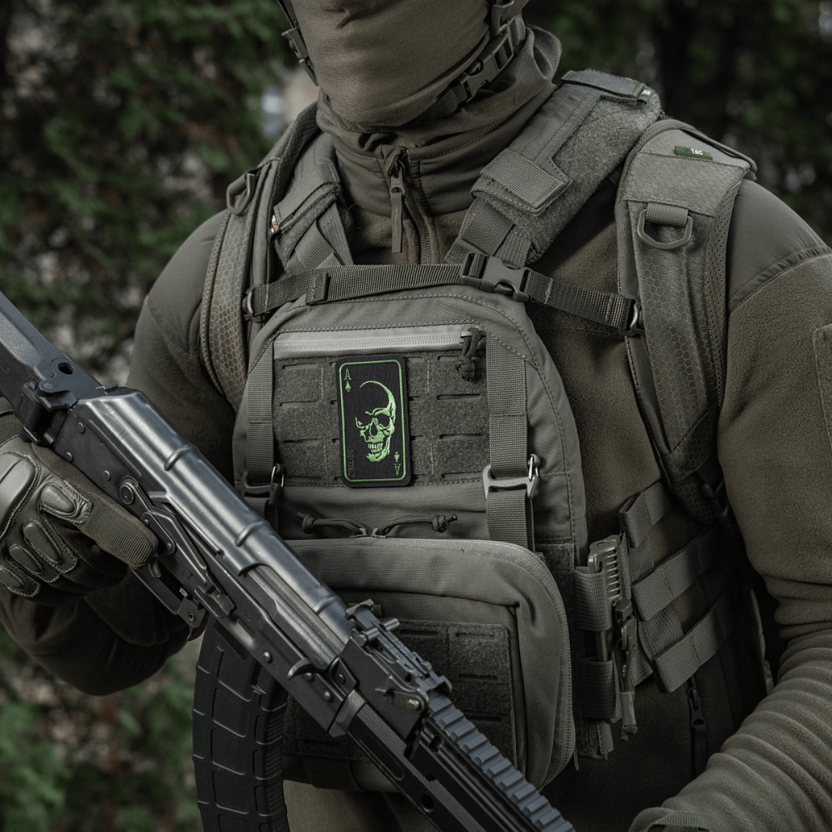 Henkilö jolla M-Tac Patch Face of War (Broderi) liivissä, kirjailtu kallo, innoittunut Vietnam-korteista, Velcro-kiinnitys, taktinen varustus.