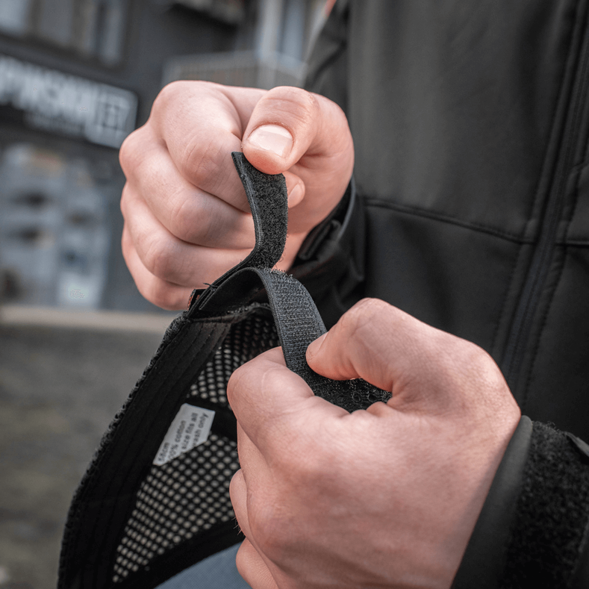Henkilö säätää Velcro-nauhaa M-Tac Mesh Flex Ripstop Baseball Capissa optimaalisen istuvuuden saavuttamiseksi.