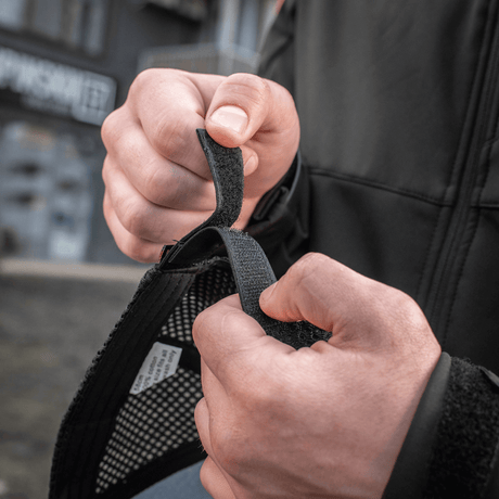 Henkilö säätää Velcro-nauhaa M-Tac Mesh Flex Ripstop Baseball Capissa optimaalisen istuvuuden saavuttamiseksi.