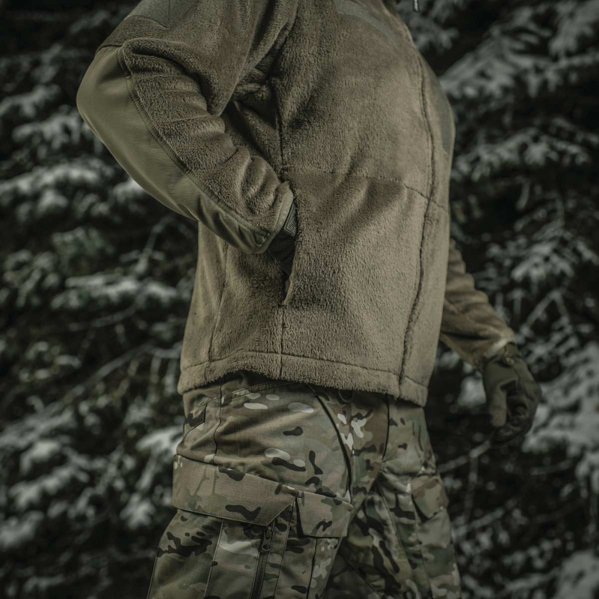 M-Tac Battle Fleece Polartec -takki käytössä armeijassa metsäympäristössä, korostaa kestävyyttä ja mukavuutta.