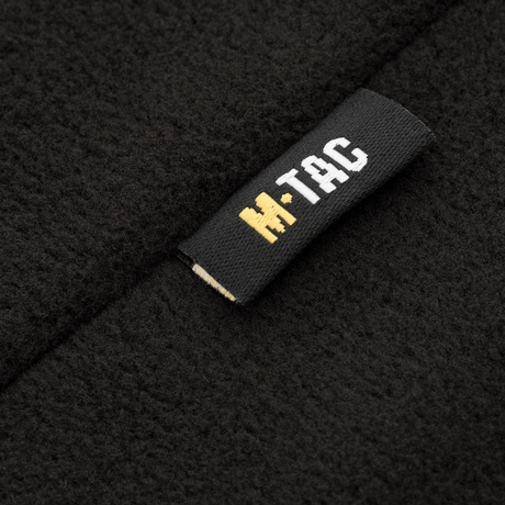 Lähikuva M-Tac Delta Fleece -takin etiketeistä, musta ja keltainen logo, fleece-materiaali, ihanteellinen ulkoiluun ja kylmiin olosuhteisiin