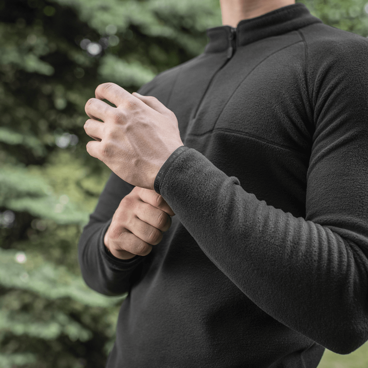 Mies pukeutuneena mustaan M-Tac Delta Polartec Raglan -takkiin Micro Series -fleecessä, täydellinen arkeen ja ulkoiluun, vetoketju ja korkea kaulus.