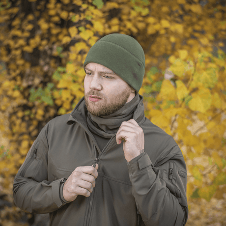 Mies pukeutuneena vihreään M-Tac Fleece Polartec Watch Cap -pipoon syksymaisemassa, sopii ulkoiluun viileissä ja kylmissä olosuhteissa.