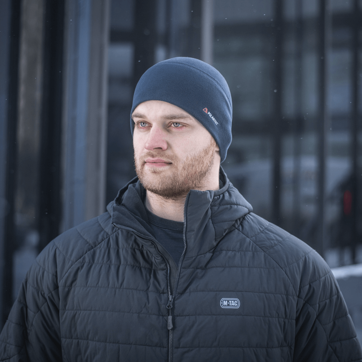Mies pukeutuneena M-Tac Fleece Watch Cap Light Polartec talvihattu, valmistettu kestävästä Polartec-fleecestä korkealla lämmöneristyksellä kylmässä säässä.