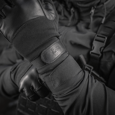 M-Tac Handsker Police Gen.2 taktiset käsineet, suunniteltu nahalla ja joustavilla paneeleilla, lähikuva kädestä Velcrolla ja logolla.