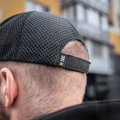 Miehellä on M-Tac Mesh Flex Ripstop Baseball Cap säädettävällä Velcro-nauhalla ja mesh-paneelilla ilmanvaihtoon ulkoilmassa.