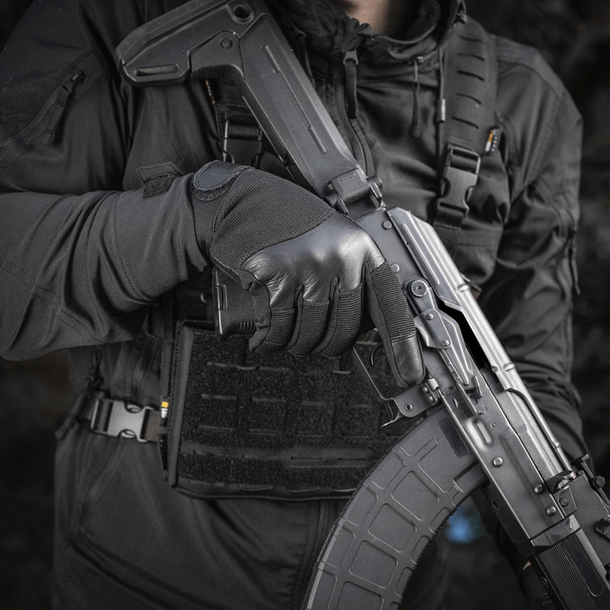 Taktiset M-Tac Handsker Police Gen.2 luotiliivin ja kiväärin kanssa, suunniteltu poliiseille ja turvahenkilöstölle varman otteen saamiseksi.