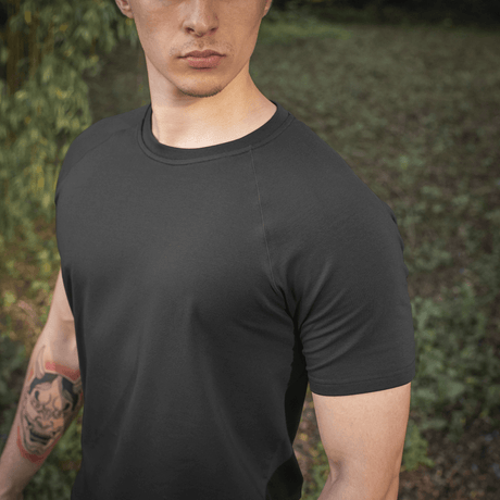 Mies pukeutunut M-Tac Raglan T-paita 93/7 optimaaliseen mukavuuteen ja liikkumavapauteen, musta, raglan-hihat, luonnollisessa ympäristössä.