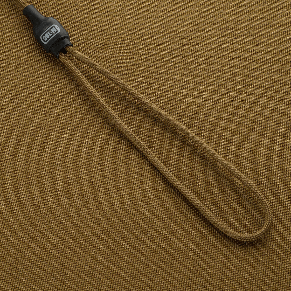M-Tac Safety Cord Medium Universal kiinnitetty beigen taustalle, joustava spiraalirakenne varusteiden turvaamiseen.