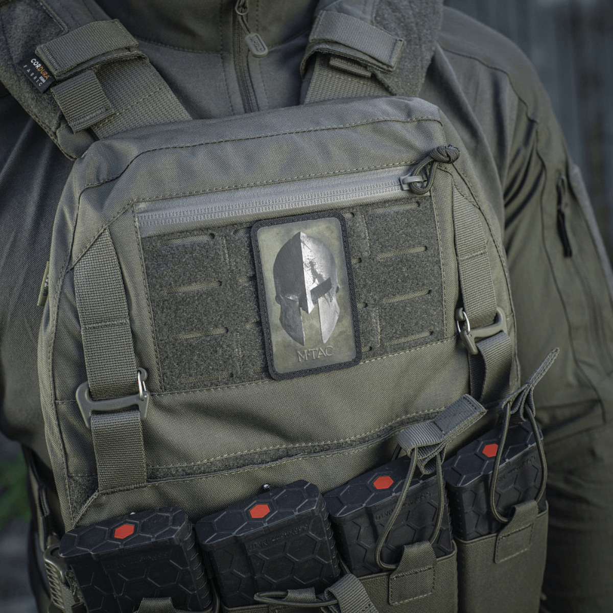 M-Tac Spartan Hjelm Patch taktillisessa liivissä, symboloi rohkeutta ja voimaa, valmistettu kestävästä Cordura 500D:stä, sopii sotilaskäyttöön.