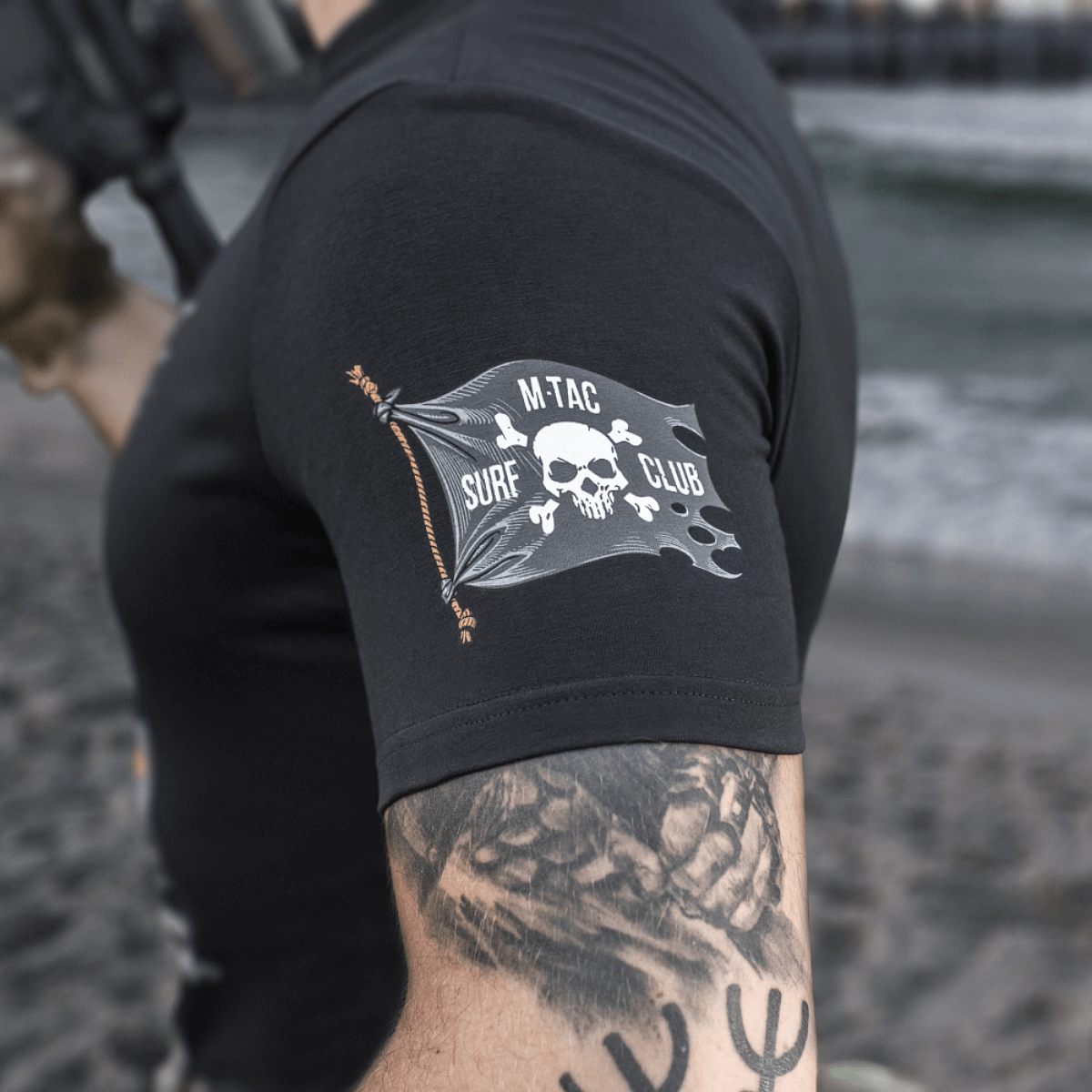M-Tac T-Shirt Surf Club ikoninen painatus, innoittajana rannikon erikoisoperaatiot; kuvattu rannalla sotilaallisen tyylin kanssa.