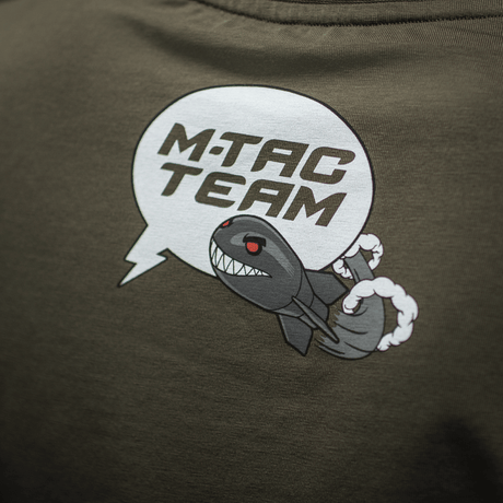 M-Tac T-Shirt Comics Drone Girl -paidassa sarjakuvapainatus, jossa pirullinen hymyilevä drooni ja teksti 'M-TAC TEAM'. Kunnioittaa ukrainalaisia droonioperaattoreita.