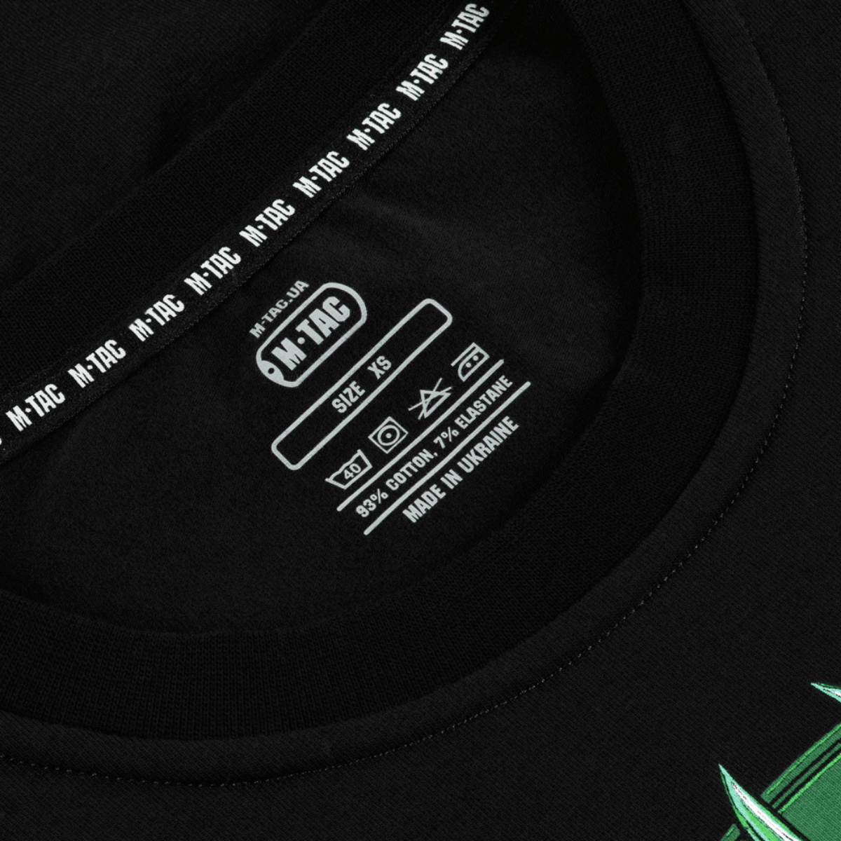 Lähikuva M-Tac T-Shirt Night Vision -etiketistä mustalla, puuvillasekoite mainittu, selkeät pesuohjeet ja koko XS.