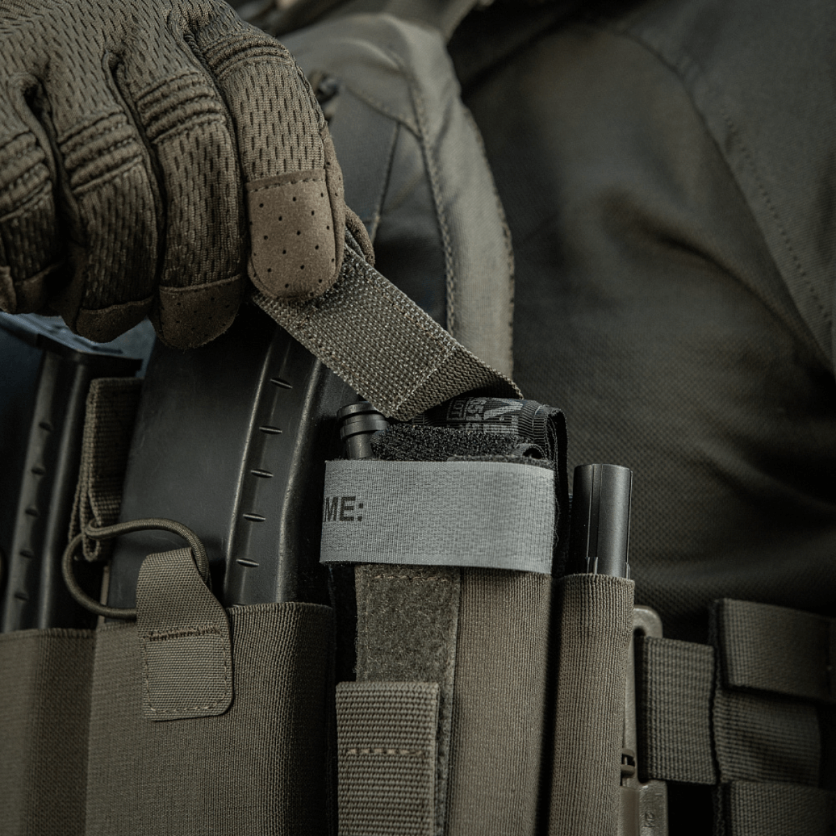 M‑Tac Tourniquet Pouch Elastic Gen.5 kiinnitetty taktiseen varusteeseen, näyttää nopean pääsyn tourniquetiin elastisella velcro-nauhalla