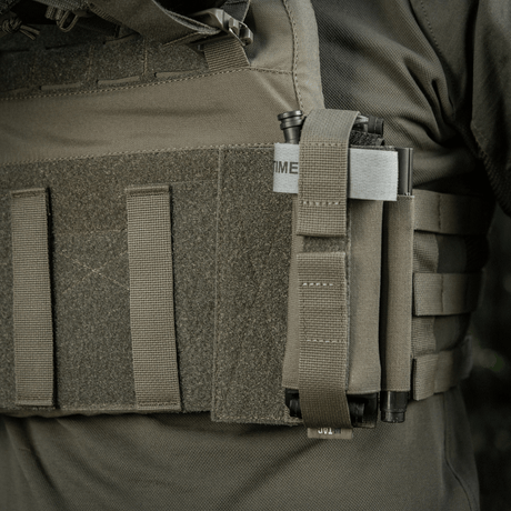 M‑Tac Tourniquet Pouch Elastic Gen.5 kiinnitetty taktiseen varusteeseen, näyttää turvallisen kiinnityksen elastisella nauhalla ja velcrolla