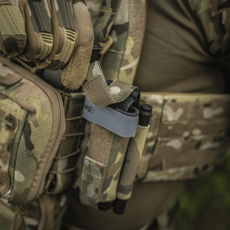 M‑Tac Tourniquet Pouch Elastic Gen.5 kiinnitetty taktiseen varustukseen camo-mallissa, tourniquet säilytetty paikoillaan.