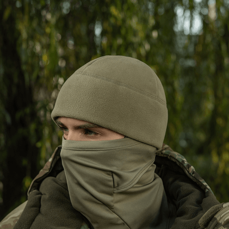 Henkilö käyttää M-Tac Watch Cap Elite Fleece Beanie Hat Slimtexiä luonnossa, sopii kylmään ja taktiseen käyttöön, maastokuvioidun takin kanssa