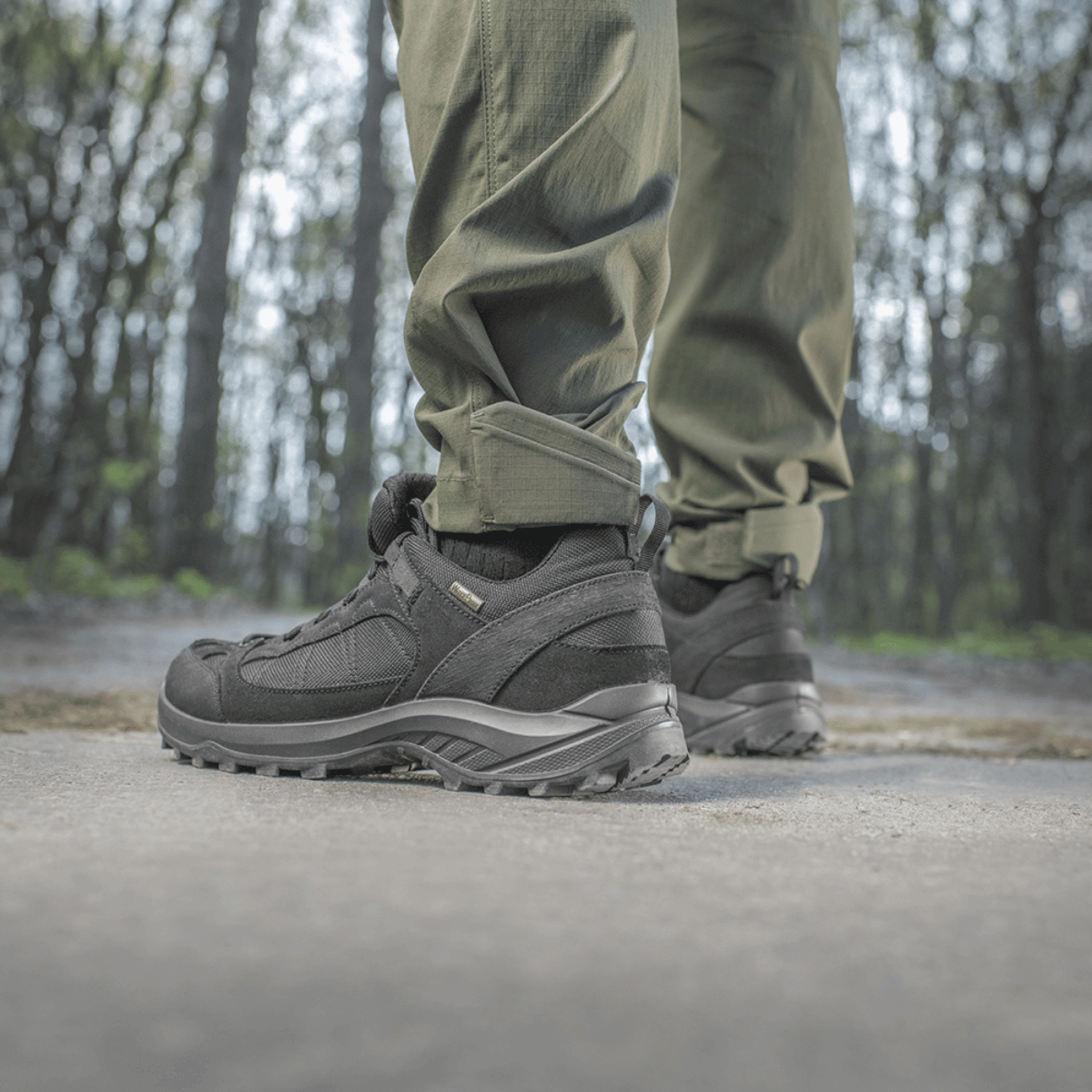 Henkilö pukeutuneena M-Tac Aggressor Summer Flex -housuihin metsässä, näyttää housujen mukavuuden ja kestävyyden luonnollisessa ulkoilumaisemassa.