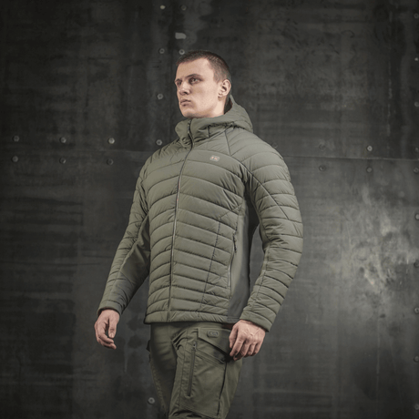Mies pukeutuneena khakinväriseen M-Tac Jarl -takkiin, valmistettu Toray mechanical stretch -nylonista ja G-Loft-täytteellä maksimaaliseen lämpöön ja mukavuuteen.