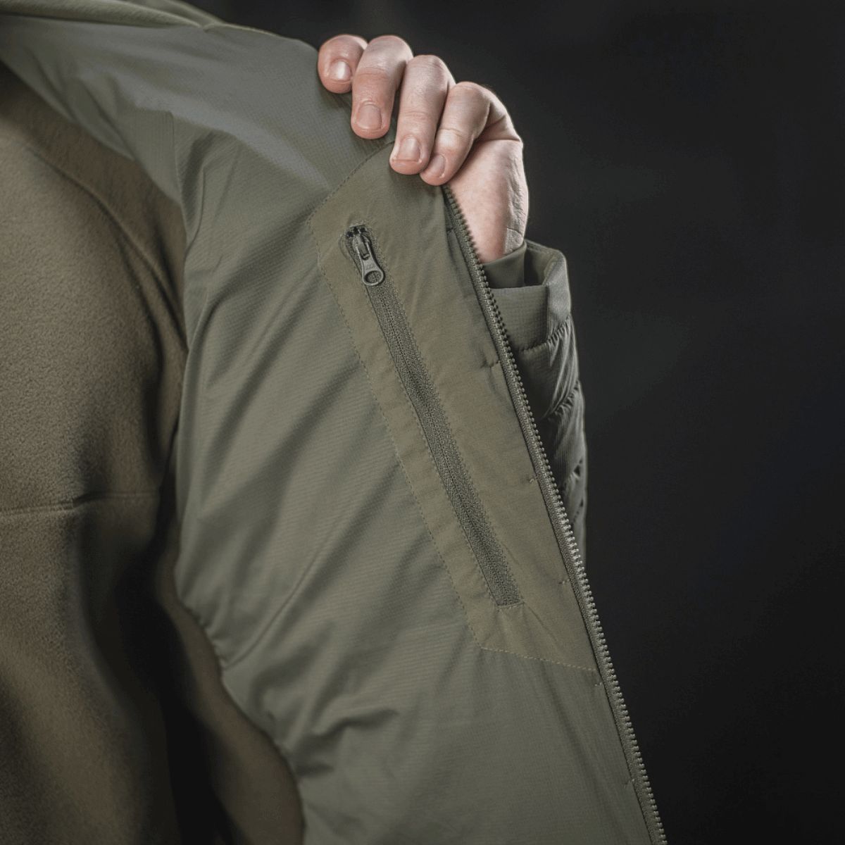 Yksityiskohta M-Tac Jarl -takista, näkyvissä hengittävä Toray stretch -nylon ja vetoketjutasku; sopii välikaudelle ja suojaksi kylmältä.