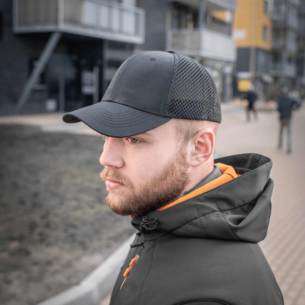 Miehellä on M-Tac Mesh Flex Ripstop Baseball Cap mesh-paneeleilla jalkakäytävällä, ulkoilupäähine säädettävällä Velcro-nauhalla.