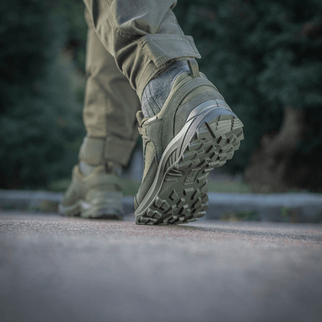 Mies käyttää Tactical Sneakers Demi-Season -kenkiä – kevyt ja mukava luonnossa, näyttää kengän tukevan pohjan ja materiaalit.