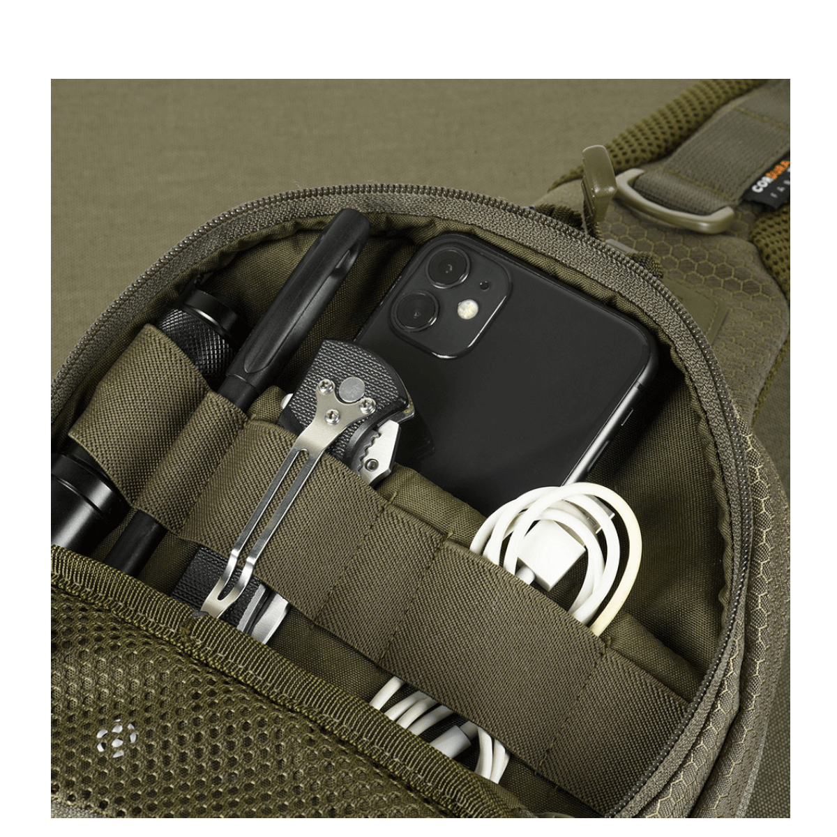 Yksityiskohta M-Tac Buckler Taske Elite Hexistä, taskut täynnä työkaluja ja elektroniikkaa, esittelee älykkään suunnittelun toiminnallisuuden.