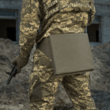 M-Tac Istuinalusta vyöllä käytössä sotilaalla maastokuviollisessa univormussa, nähtynä takaa maanpinnalla.