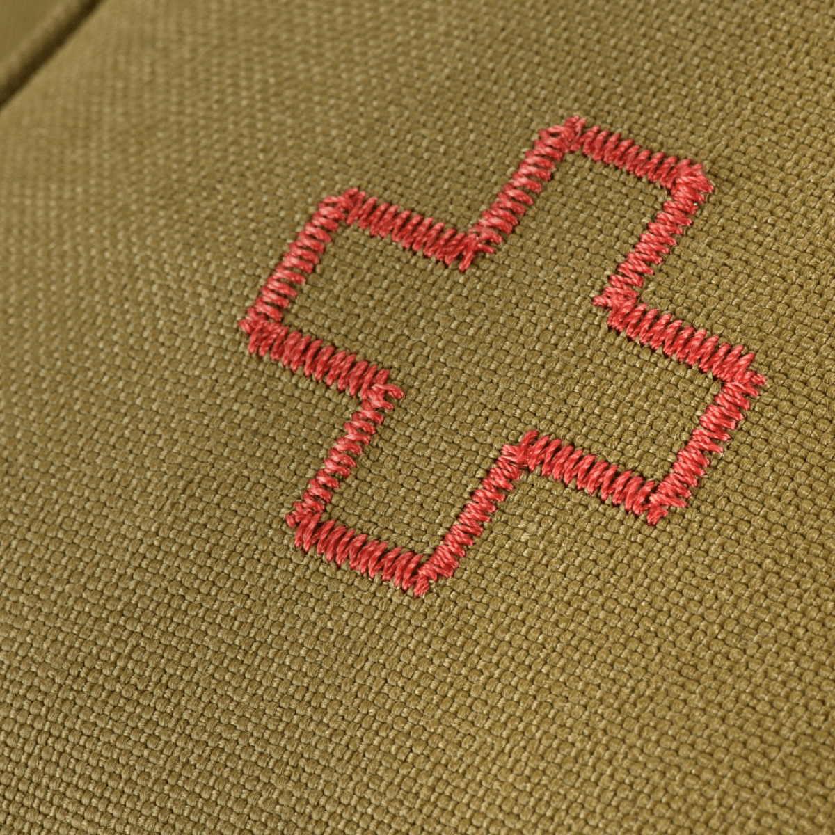 Lähikuva M-Tac Medical Pouch Rip Offista, jossa punainen ristikirjailu oliivinvihreällä taustalla, suunniteltu ensiapuun ja nopeaan käyttöön.