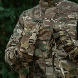 M-Tac-laukku PVS-14 maastokuvioinnilla, henkilö pitelee sitä taktisiin vaatteisiin pukeutuneena ulkona.