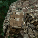 M-Tac-laukku PVS-14 maastokuvioituna, henkilö pitää sitä metsässä; Fastex-solki ja joustavat remmit turvalliseen säilytykseen.