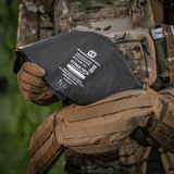War Belt ARMOR pidetään taktisesti varustetun henkilön kädessä camo-liivin ja MOLLE-hihnojen kanssa, korostaa M-Tac-tuotteen käytännöllisyyttä.