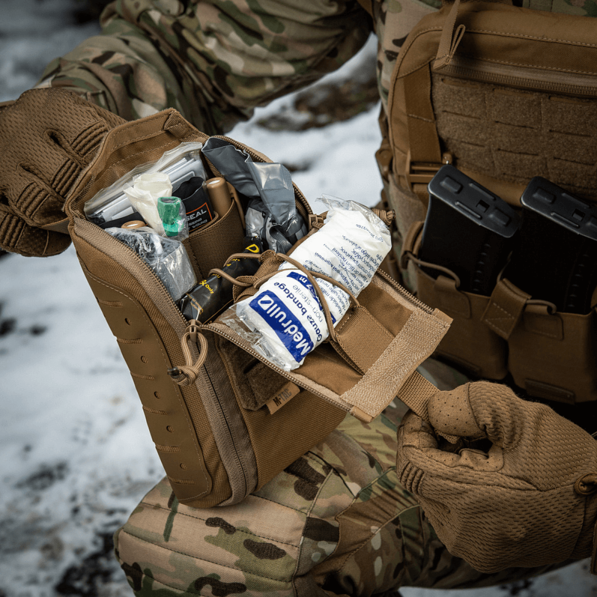 M-Tac Medical Pouch Elite Rip Off avattuna kentällä, järjestetty sisältö joustavilla hihnoilla.