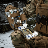 Sotilas lumessa käyttää M-Tac Medical Pouch Elite Rip Off -pussia, avoin ja selkeästi järjestetty sisältö.