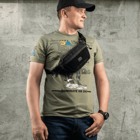 Mies käyttää M-Tac Tactical Waist Bag Gen.II Elite mustaa, sopii taktiseen ja arkikäyttöön, tehty kestävästä Cordura 1000D -materiaalista